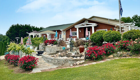 Mediterranean Cellars - Fauquier Wine - view of winery surrounded by colorful landscaping, stones, and sculptures